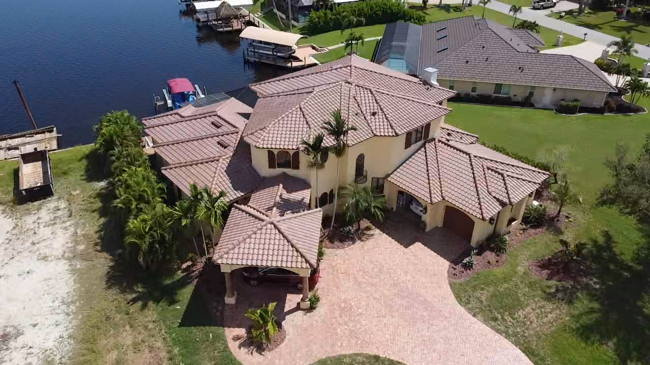 Complex two-story pale yellow home with a reddish tan tile roof completed by Mako Roofing and Restoration